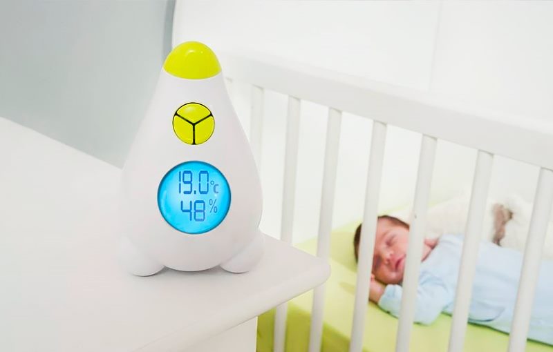 Термометр около кроватки с новорожденным