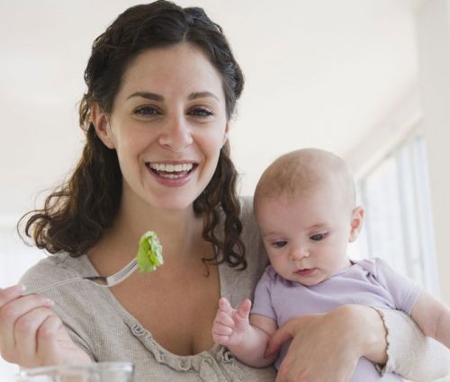 Женщина с младенцем ест салат