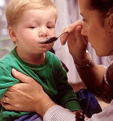 Child receiving medicine. Cough syrup