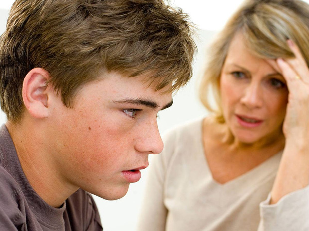Подросток с озабоченным выражением лица слушает расстроенную маму