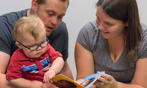 parents reading book with young child